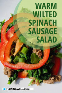 Warm wilted spinach sausage salad on a plate