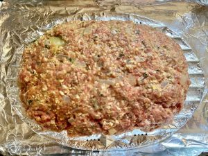 freeform shaped meatloaf in a pan before baking