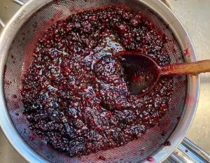 canned blackberry syrup in the sieve