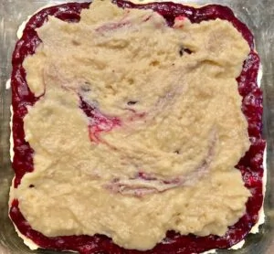 rhubarb blueberry coffee cake batter spread on top of filling