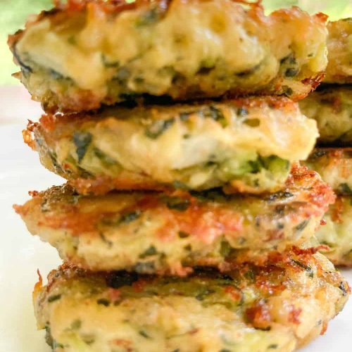 zucchini fritters with cheese stacked on a plate