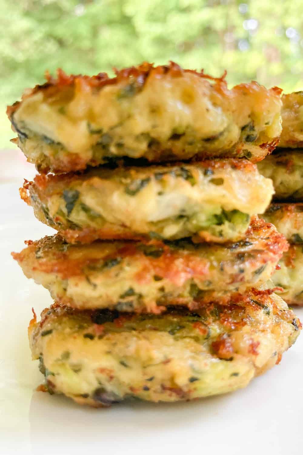 zucchini fritters with cheese stacked on a plate