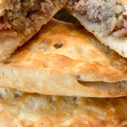 easy savory hand pies stacked and one sliced open to reveal the meat filling